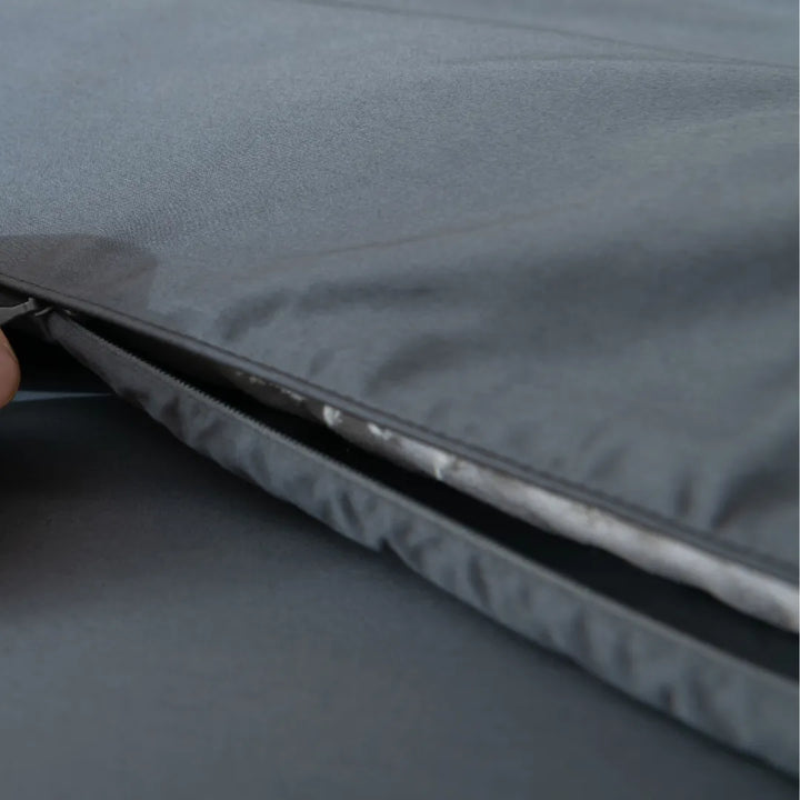 Close-up of a Linenly Luxe Sateen Quilt Cover in Charcoal with a partially unzipped zipper on a gray background.