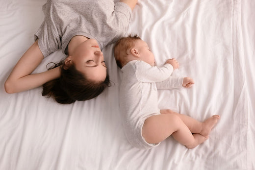 a mother and kid sleeping in a bed with white bamboo bed sheet 