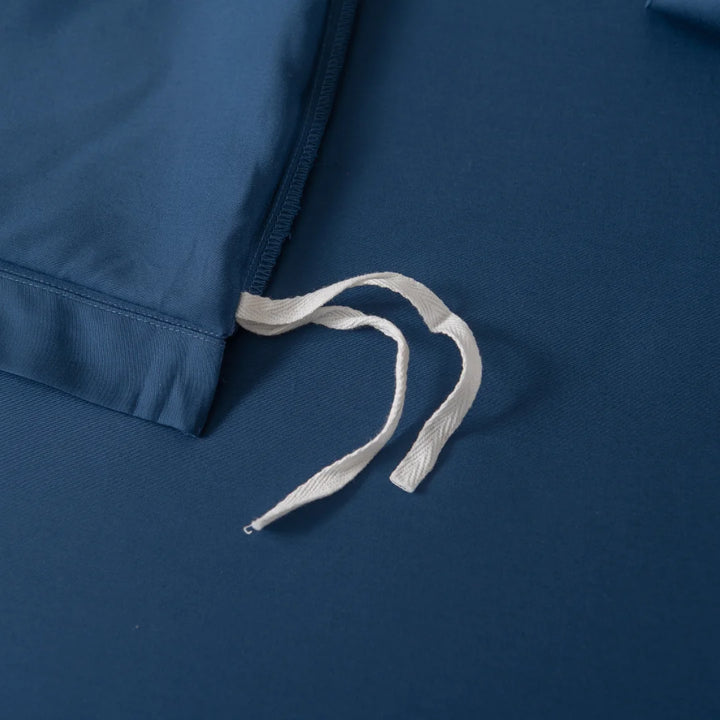 A close-up of Linenly's Bamboo Quilt Cover Set - Midnight shows a dark blue bamboo fabric bed sheet with a white tie string on top, loosely arranged across the sateen weave to highlight the quilt cover's texture and smoothness.