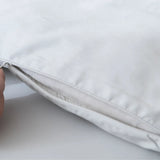 A close-up of the Linenly Luxe Cotton Sateen Quilt Cover in Silver shows its soft, long staple cotton texture as a hand holds the edge near a partially opened zipper, revealing the inner insert.