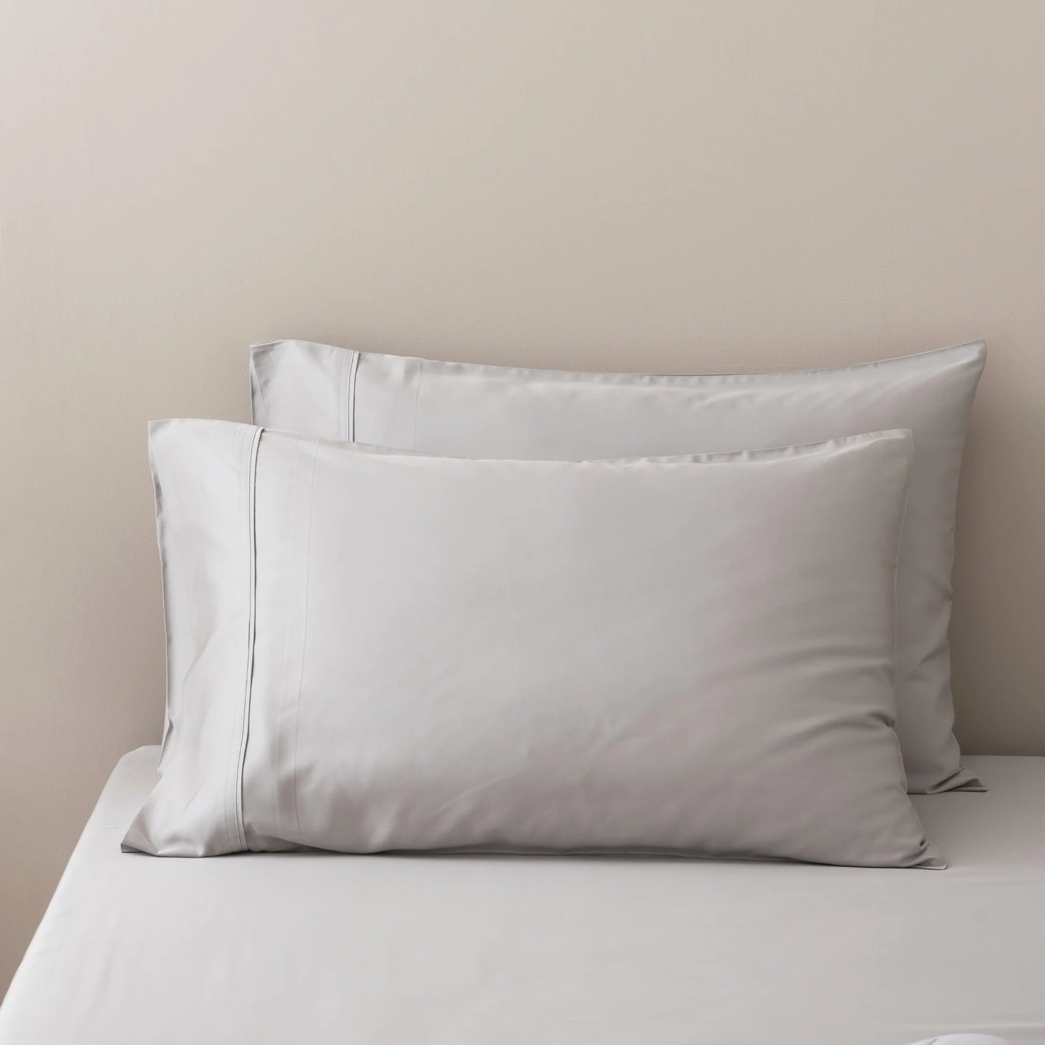 Two Linenly Bamboo Pillowcase Set - Silver pillowcases are neatly arranged against a light beige wall on a matching bed with smooth, wrinkle-free sheets, creating a calm, minimalistic scene.